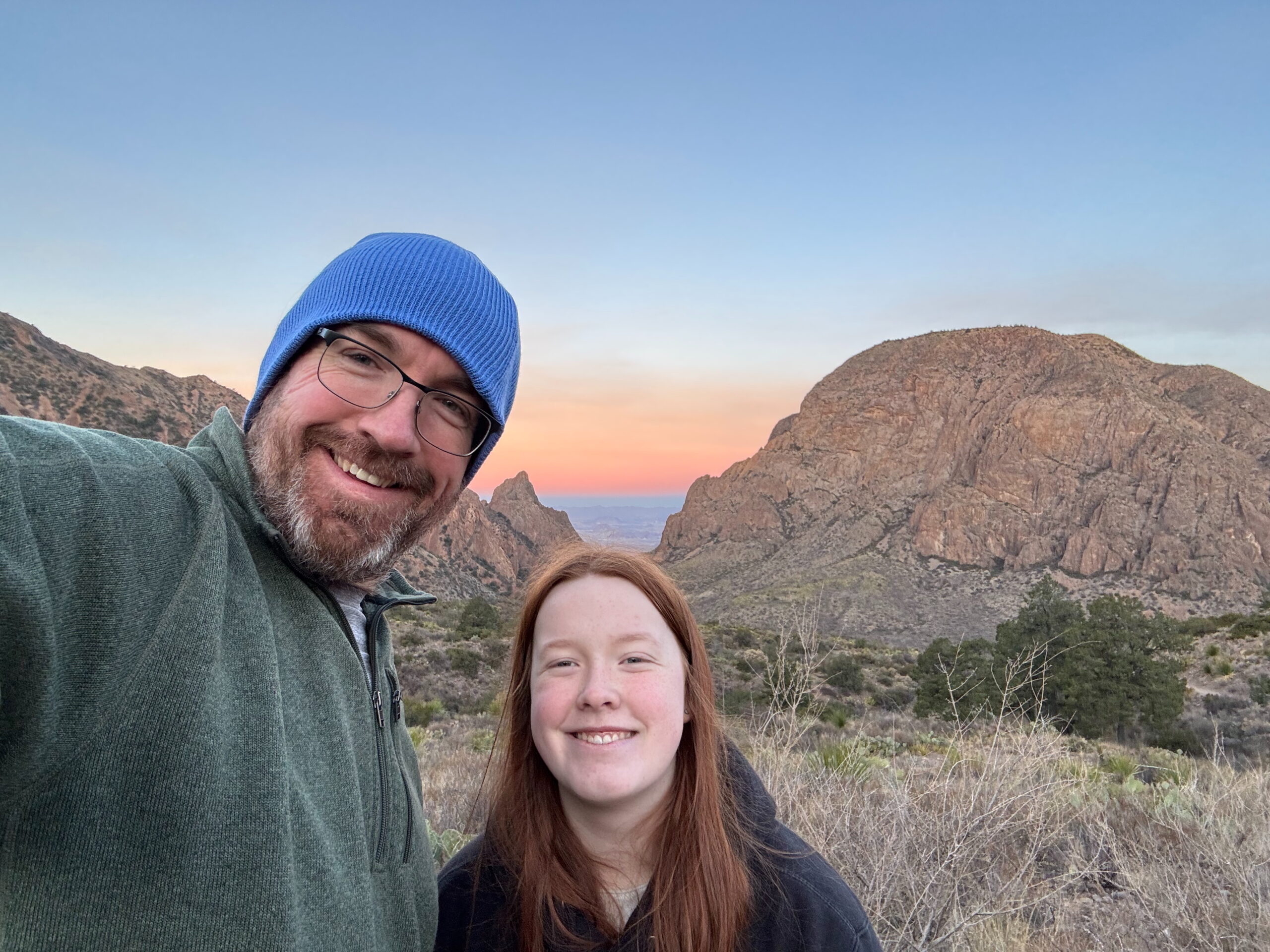 Cameron and myself at the Window Overlook at sunrise. A red sky behind us, Cami wearing a sweatshirt and me in a hat.