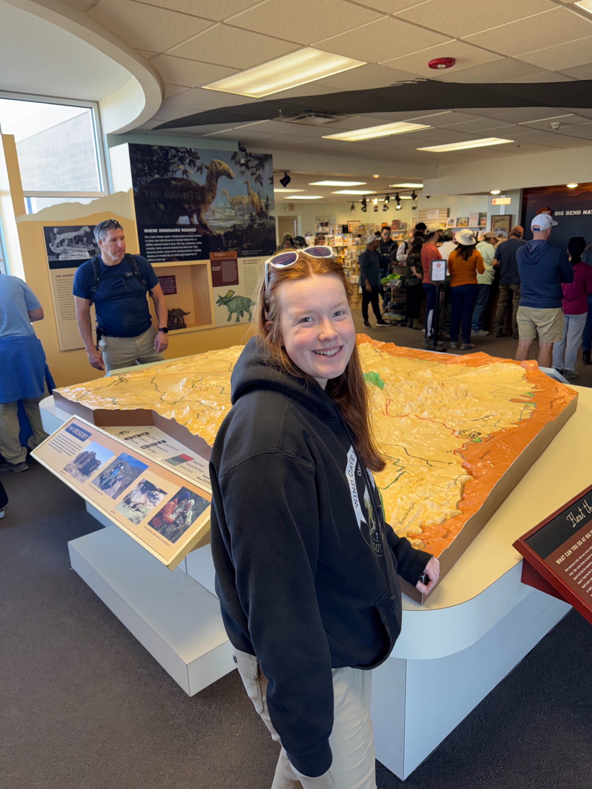 Cameron wearing a sweatshirt standing by the massive 3d map in the Big Bend Visitors Center.