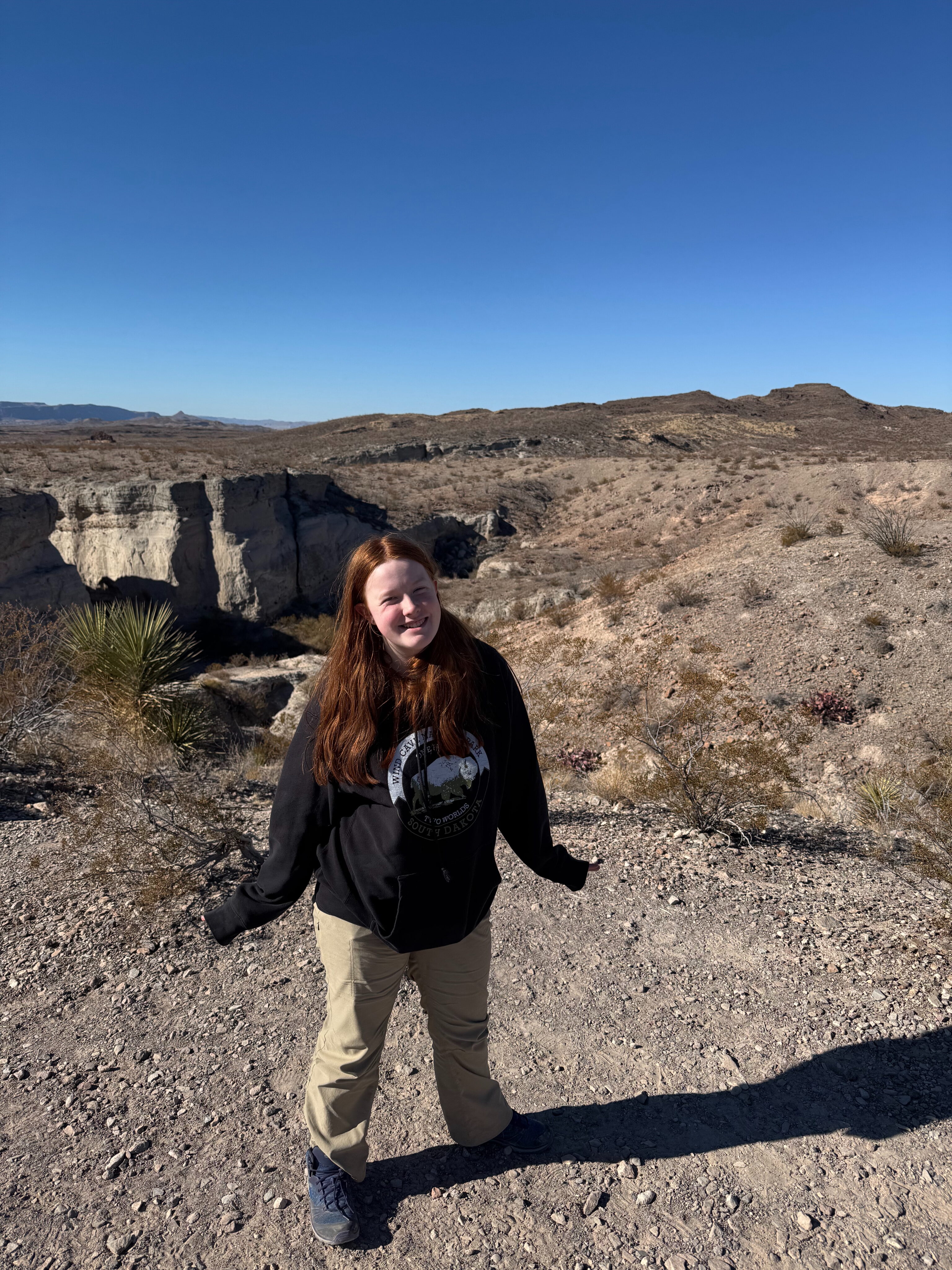 Cameron posses in the Big Bend Desert, the bad lands are right behind her with a dark blue sky.