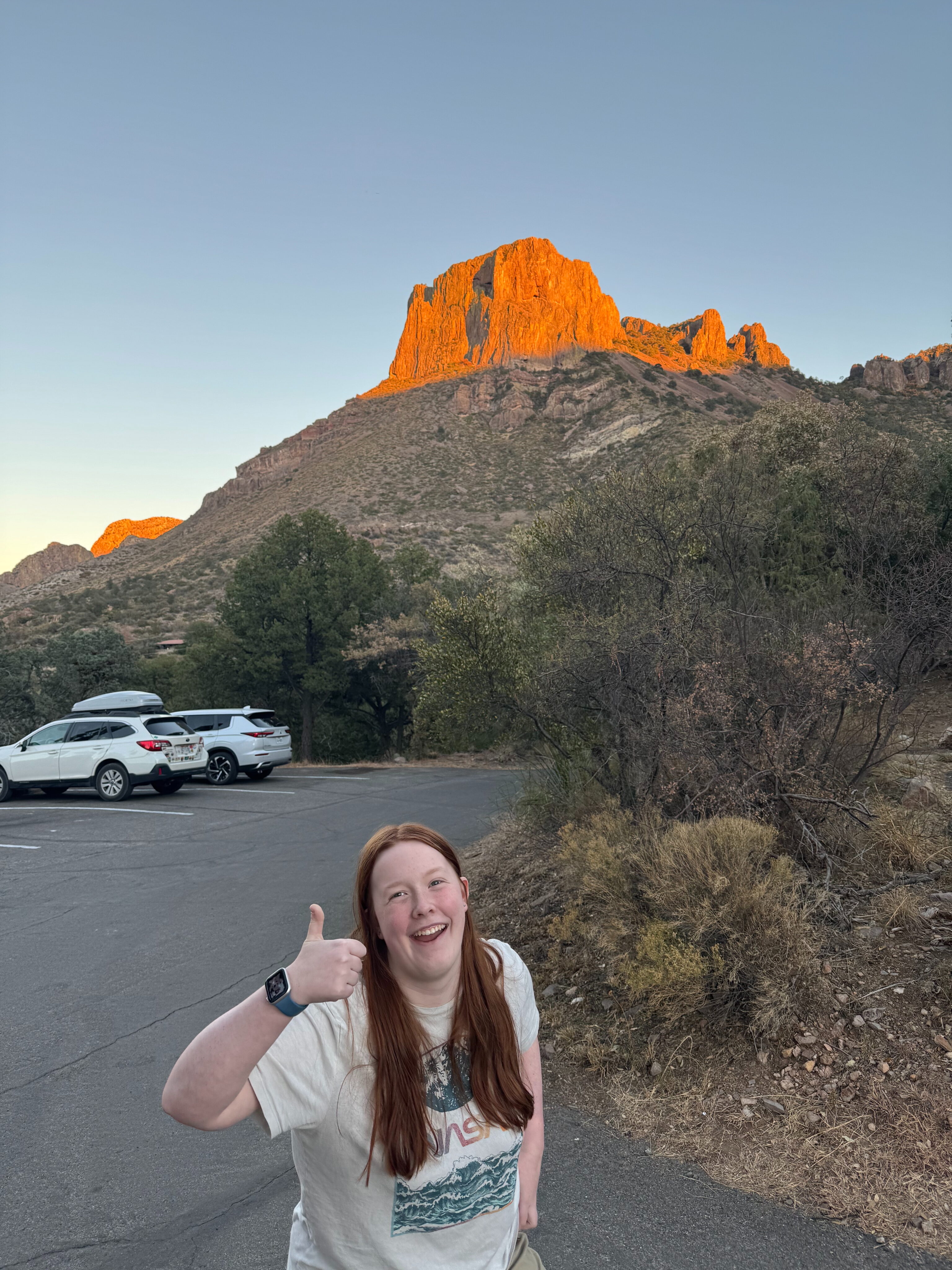 Cameron giving a thumbs up in the parking lot on the way to dinner with the last golden light hitting the tops of the mountains. 