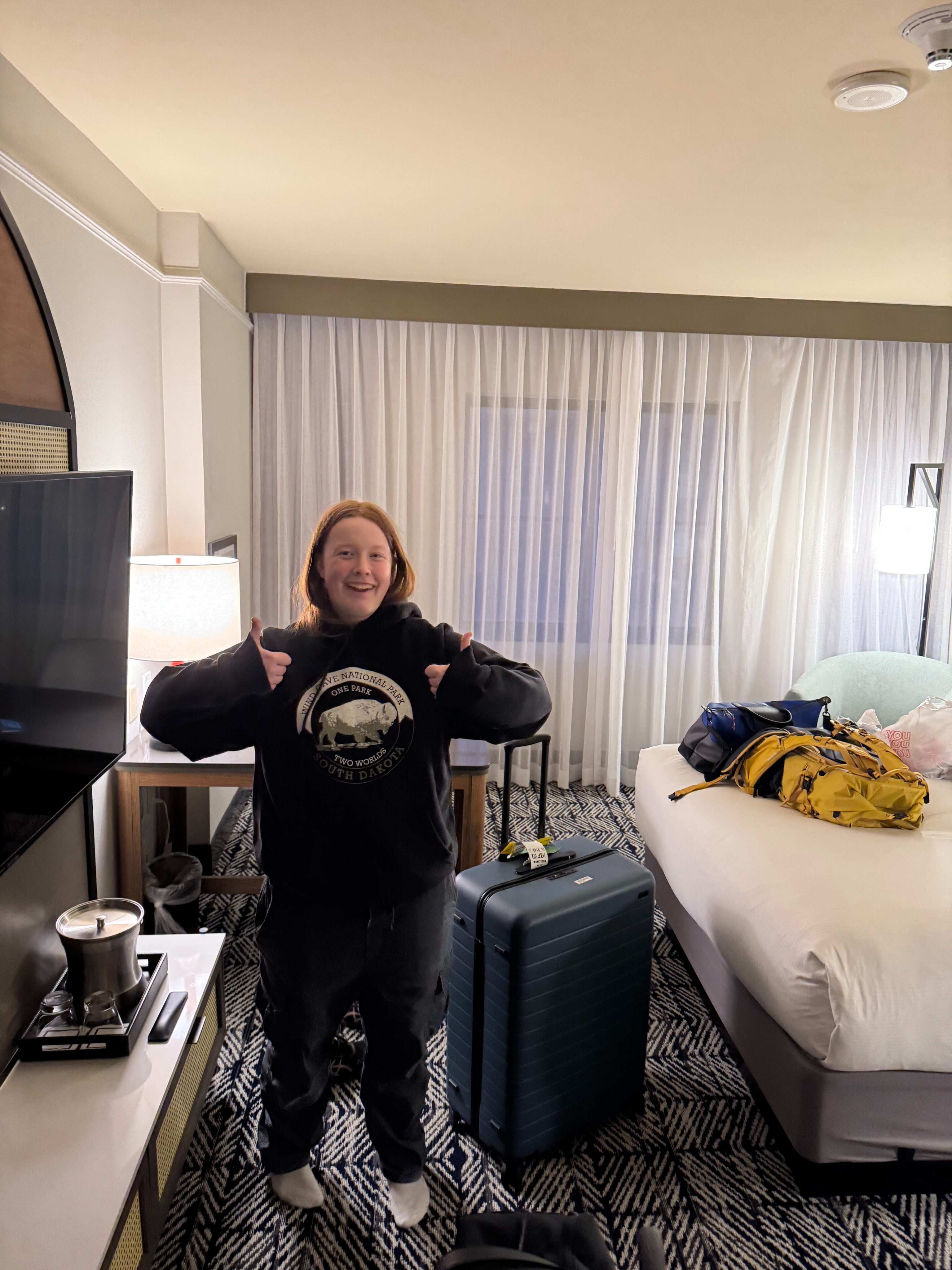 Cameron standing in the hotel room with two thumbs up at the Hilton in South Lake TX.