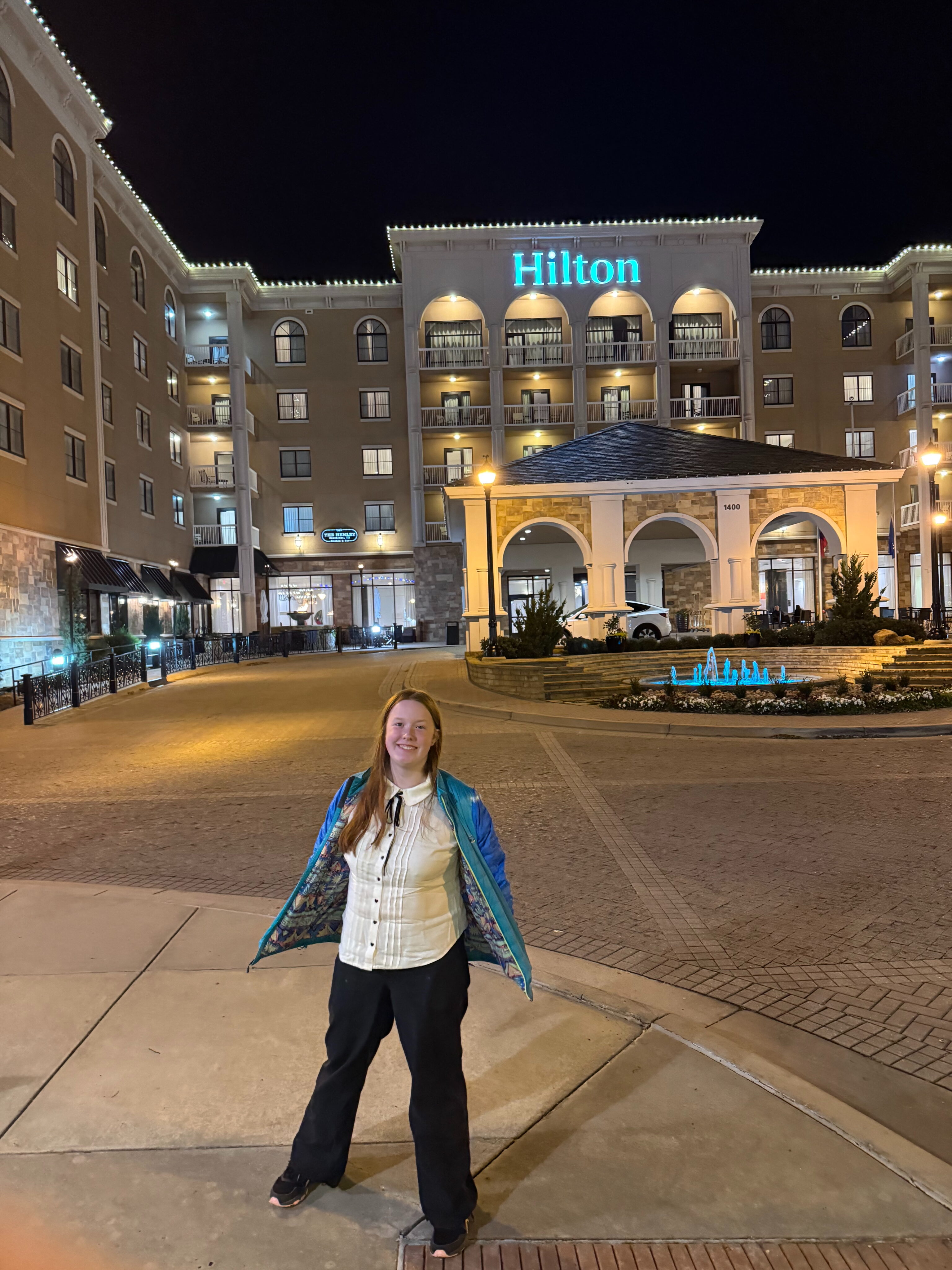 Cameron dressed up, standing on the street on New Years Eve at night in front of the Hilton in South Lake TX