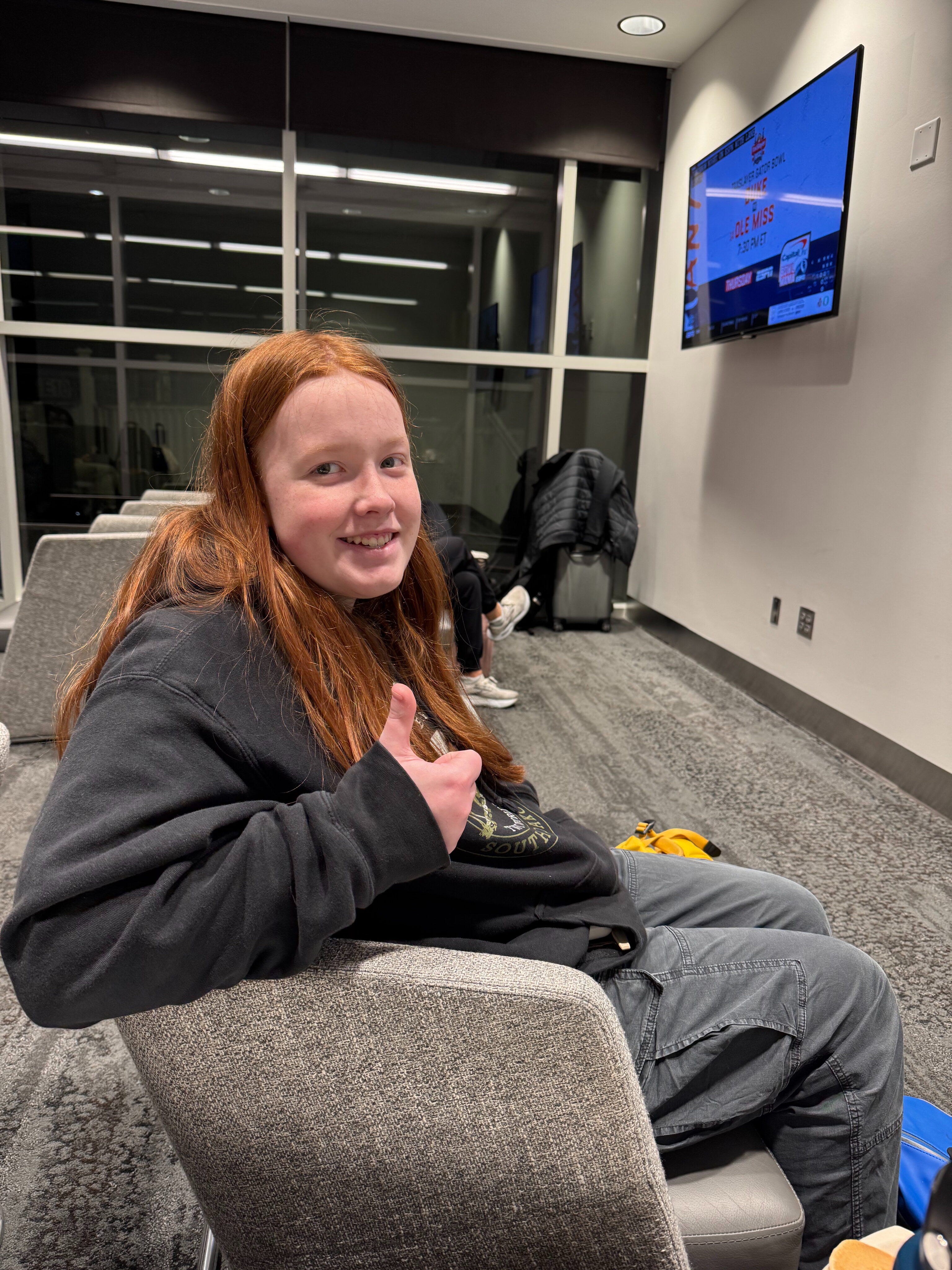 Cameron sitting in a chair at the Delta Lounge at DFW very early in the morning on New Years Day 2025.