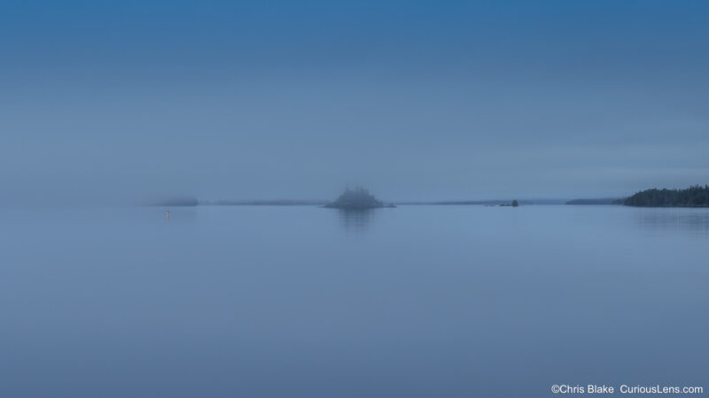 Minimalist photo of a foggy morning in Rock Harbor, Isle Royale National Park, with a buoy and Center Island barely visible through the mist