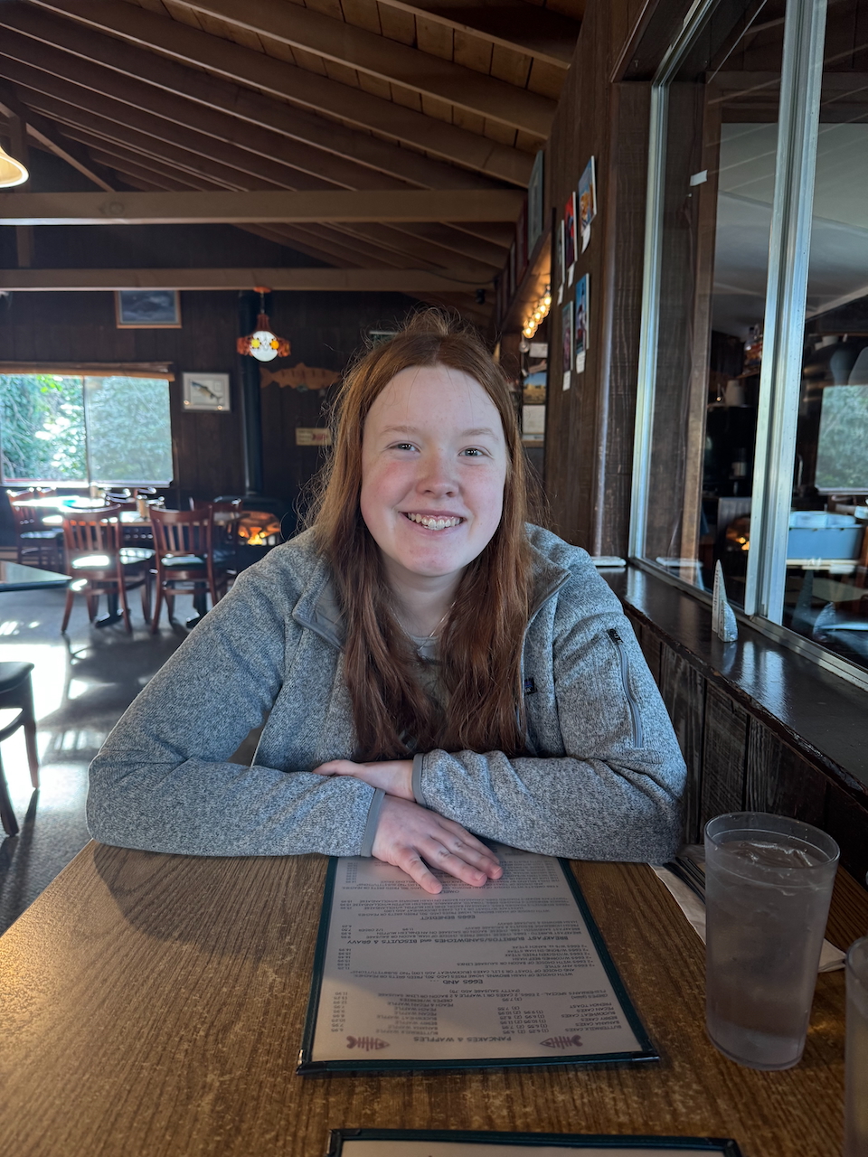 Cameron sitting at a table, all smiles, at the Indian Creek Cafe in Gold Beach OR after a sunrise shoot.