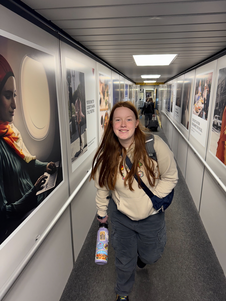 Cameron in a hoodie and a big smile as she boards the plane in Boston.