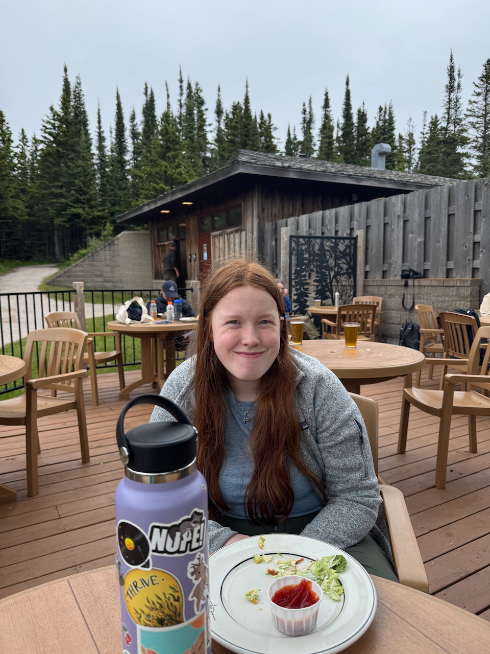 Cameron sitting with an empty plate outside at the grill in Isle Royale.