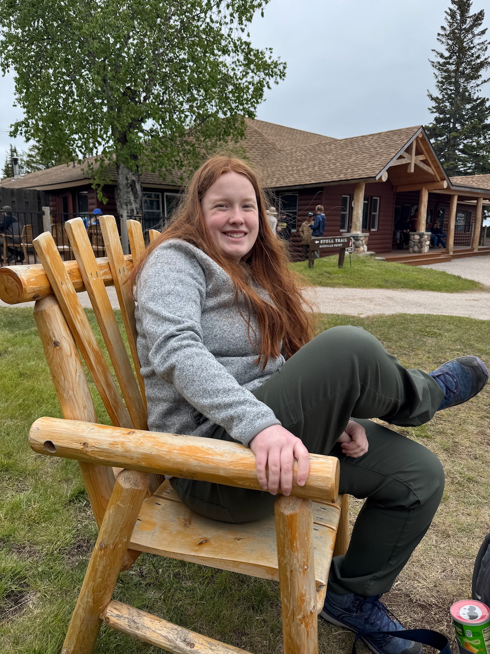Cameron sitting on a rustic outdoor chair in isle royale by the bay.