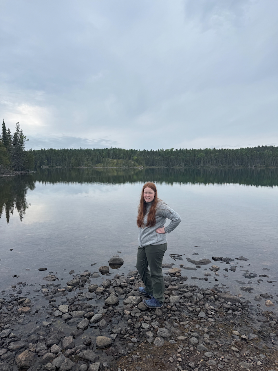 Cameron standing on the rocks in Tobin Harbor in Isle Royale - dark clouds over head.