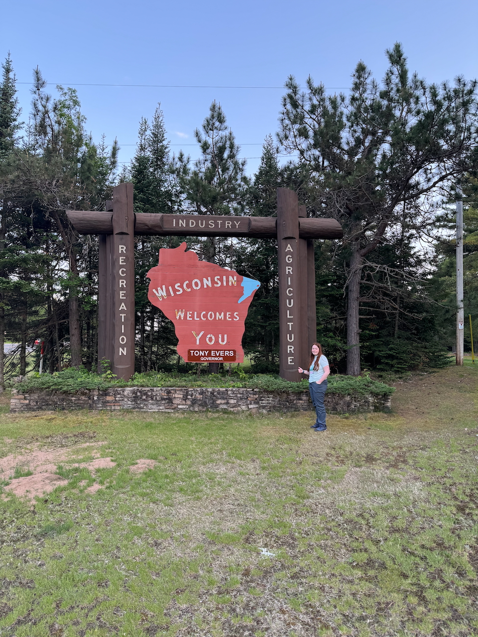 Cameron standing on the grass giving a big thumbs up for the Wisconsin Welcomes You sign.