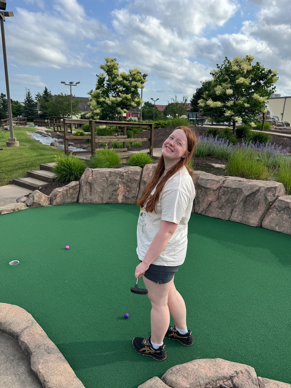 Cameron smiling while playing mini golf at Sawmill Adventures Park.