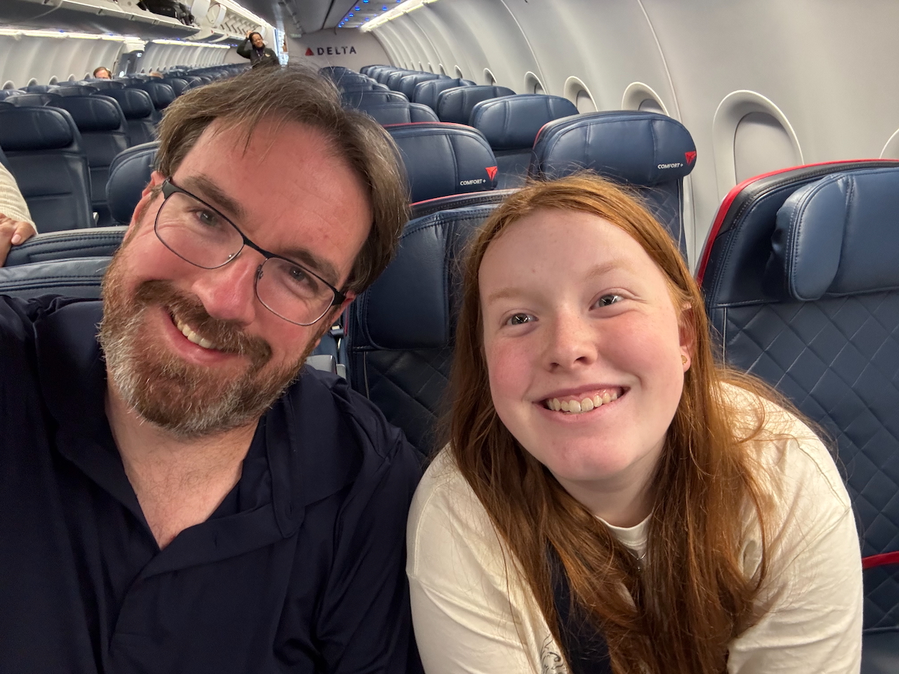 Cameron and me seated on the Delta Airlines flight with big smiles as we get ready to take off and fly home.