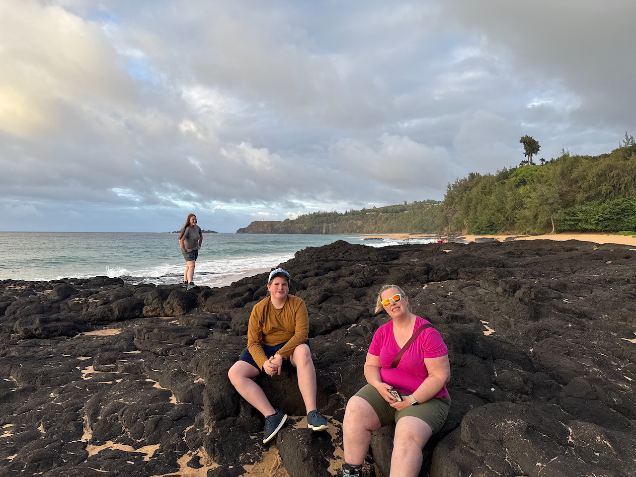 Cat and Collin sitting together on lava rocks at Secret Beach.