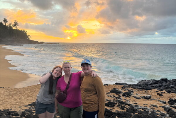 Cat, Collin, and Cameron smiling on the lava rocks at Secret Beach.