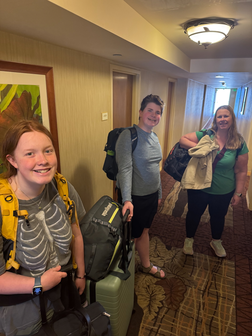 Family walking out of Hilton hotel with luggage.