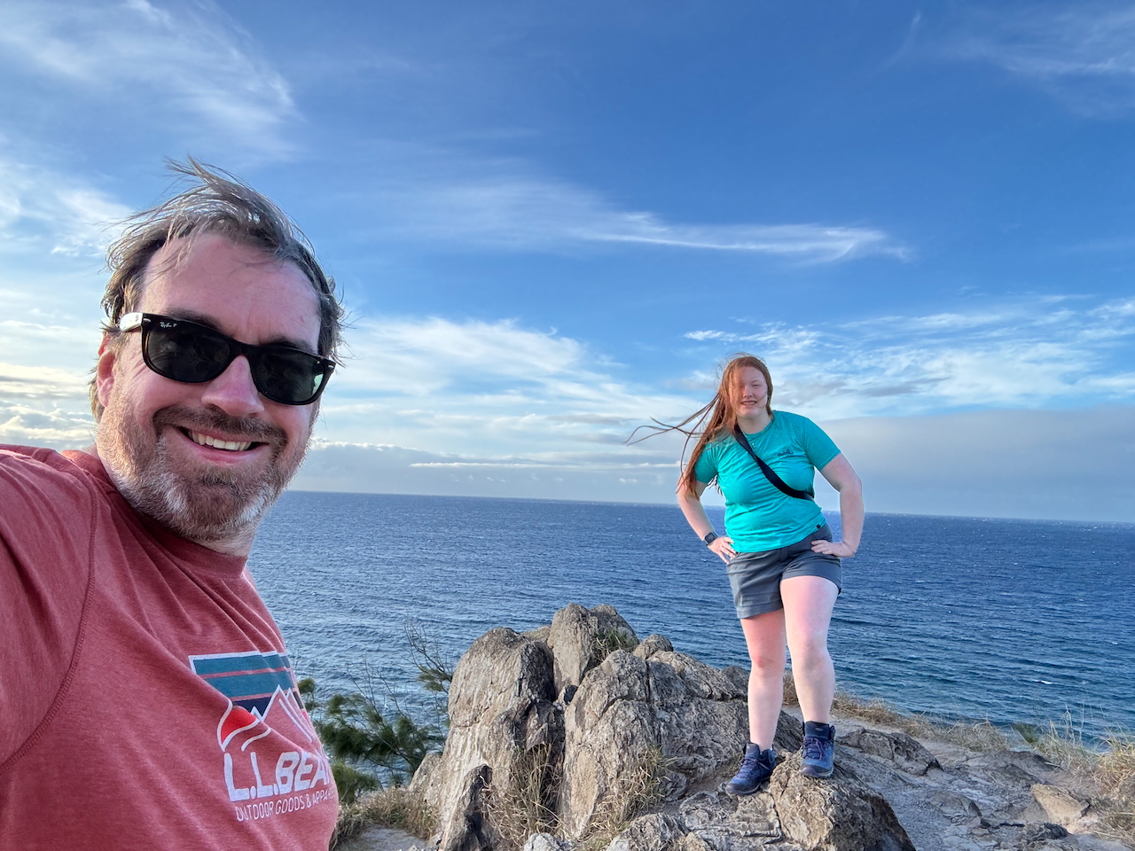 Father and daughter at rocky Maui coastline.