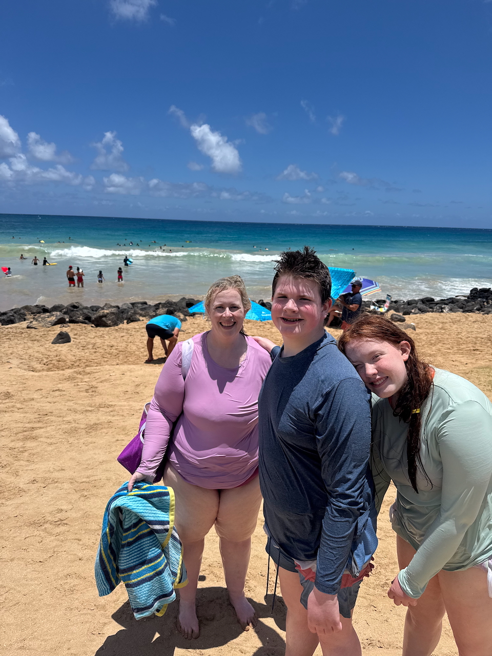 Cat, Collin, and Cameron together on the sandy shore of Poʻipū Beach.