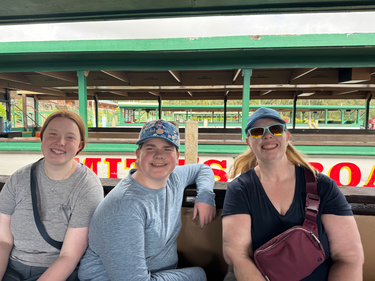 Cat, Collin, and Cameron smiling while seated on a boat in Kauaʻi.