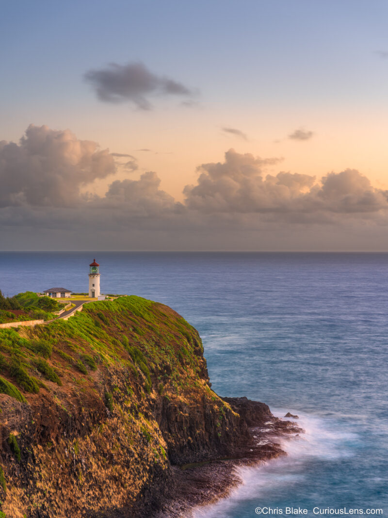 Pastel sunrise at Kilauea Lighthouse on Kauai with soft sky colors, ocean movement, and cliffs in early morning light.