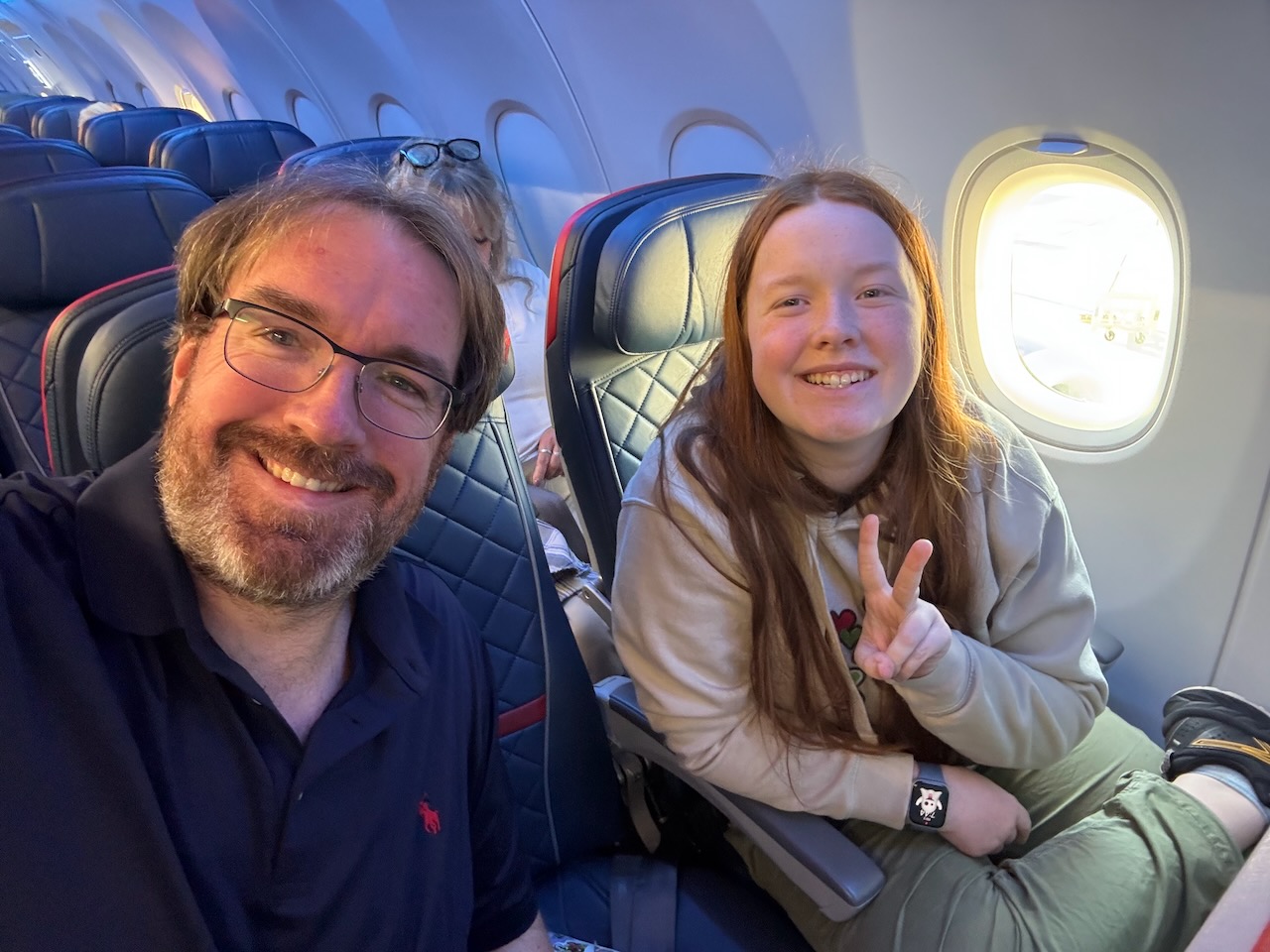 Chris and Cameron smiling together on the Delta flight from Boston to Minneapolis, starting our Voyageurs National Park adventure.