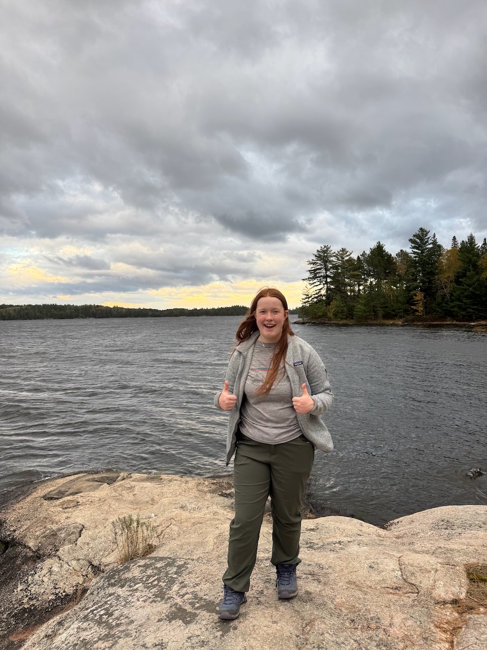 Cameron standing on the rocky shoreline at Ash River in Voyageurs National Park under dramatic clouds.
