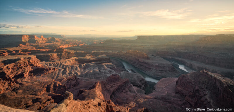 Warm early sunset over Dead Horse Point State Park in Utah, with the Colorado River winding through the canyon below and golden light glowing across the desert landscape.