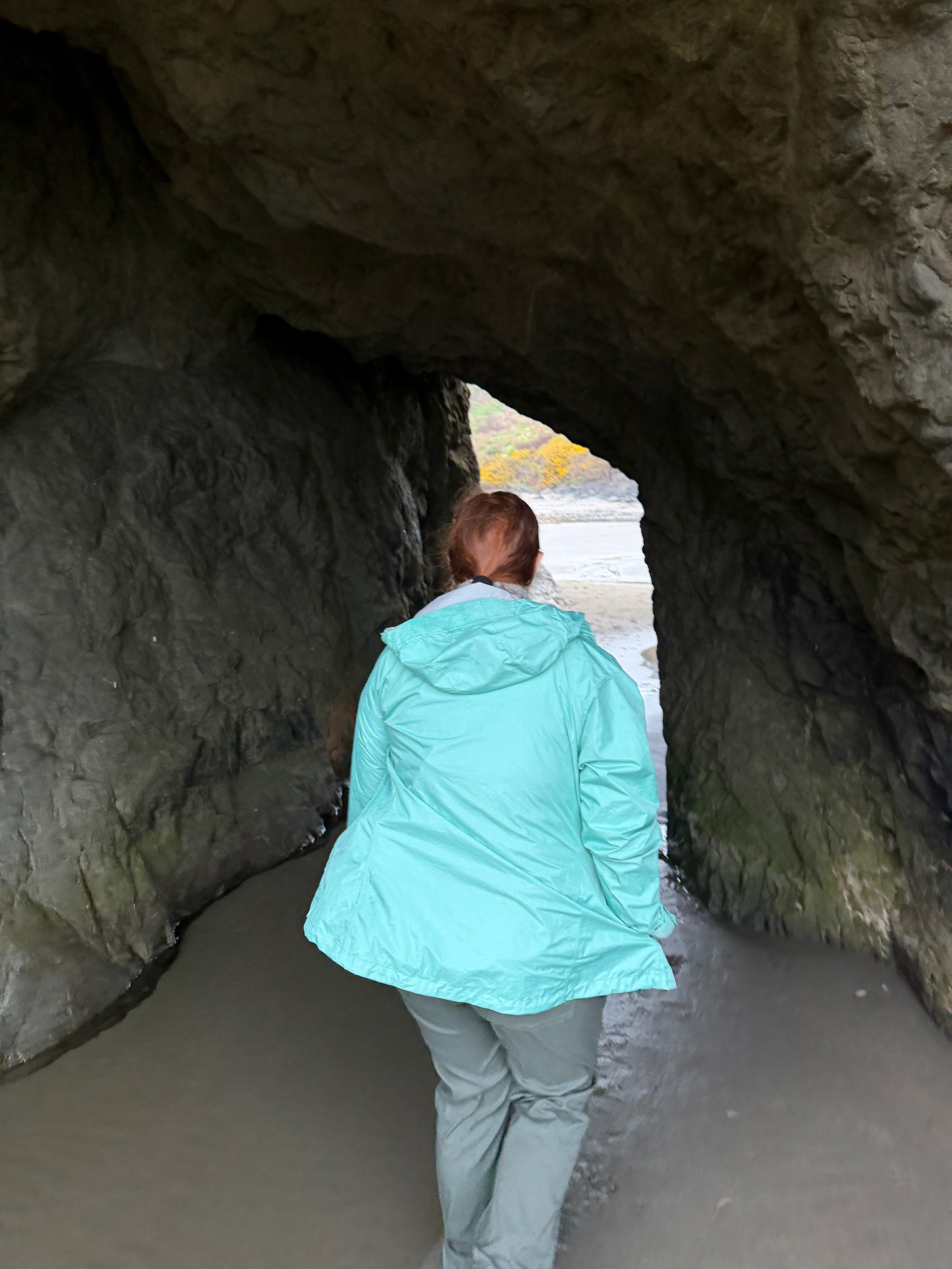 Cami walking through a small sea cave on Bandon Beach.