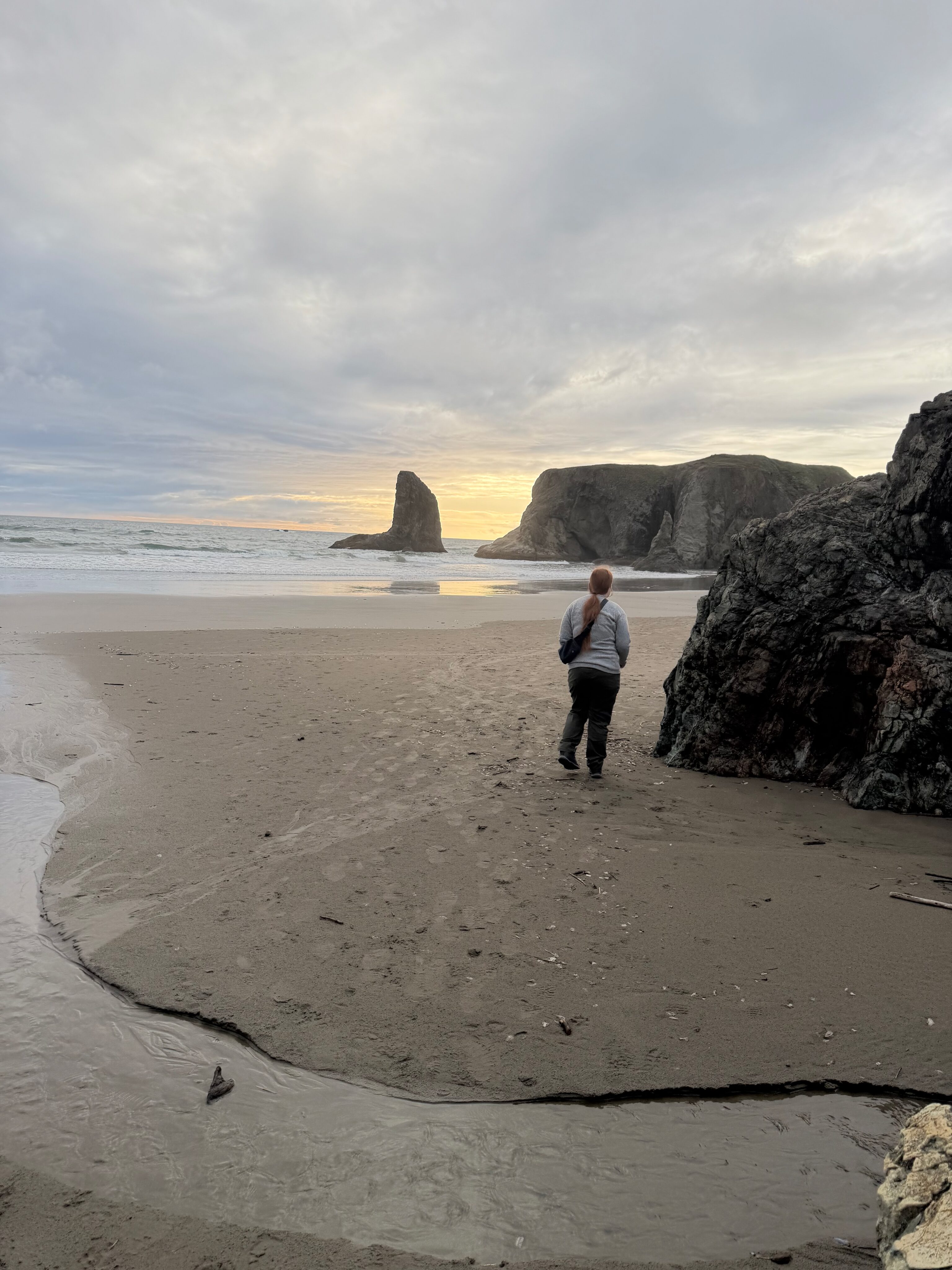 Cami walking along Bandon Beach at sunset near the sea stacks.