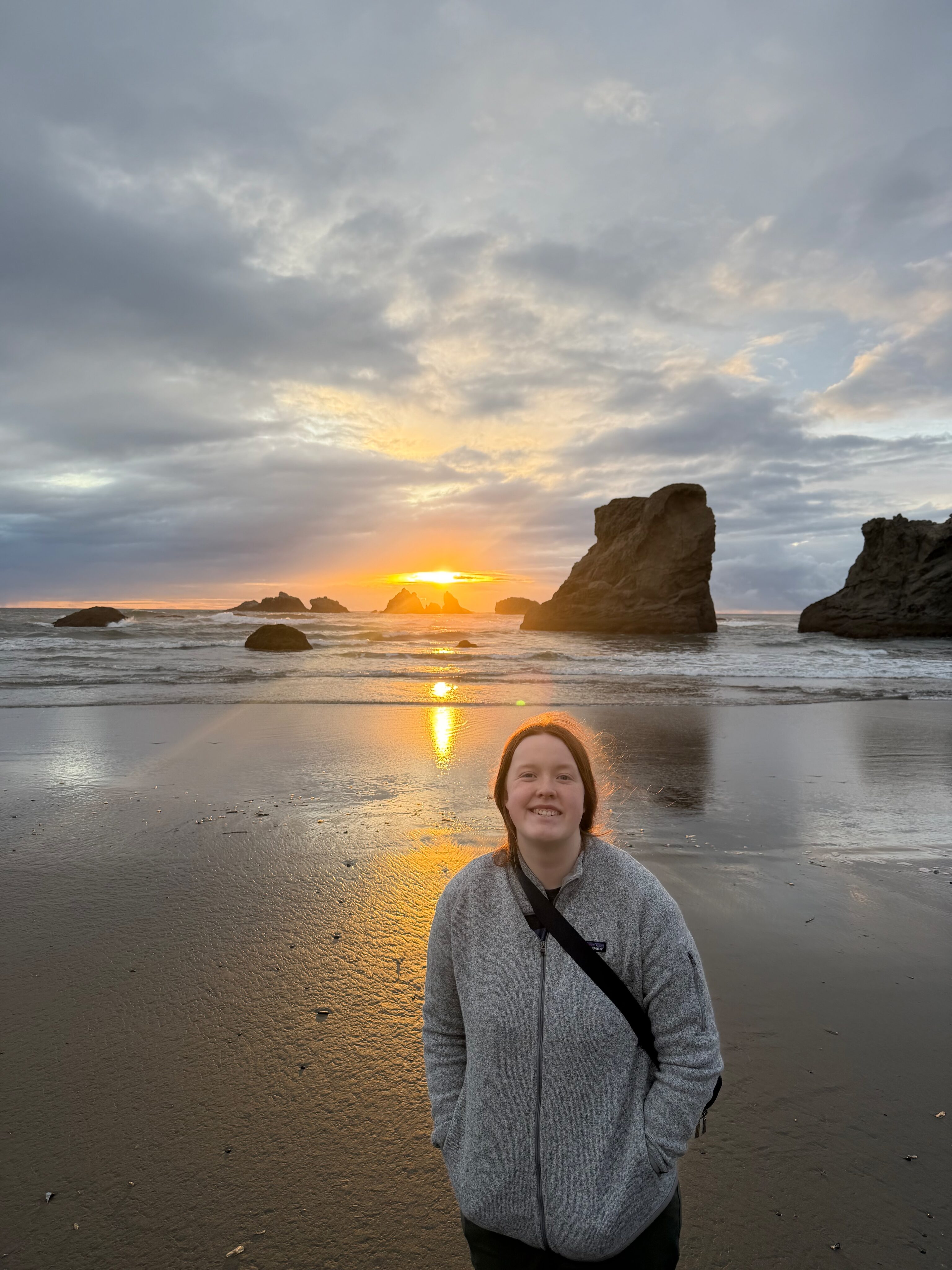 Sunset over Bandon Beach with sea stacks and golden light reflecting on the wet sand.