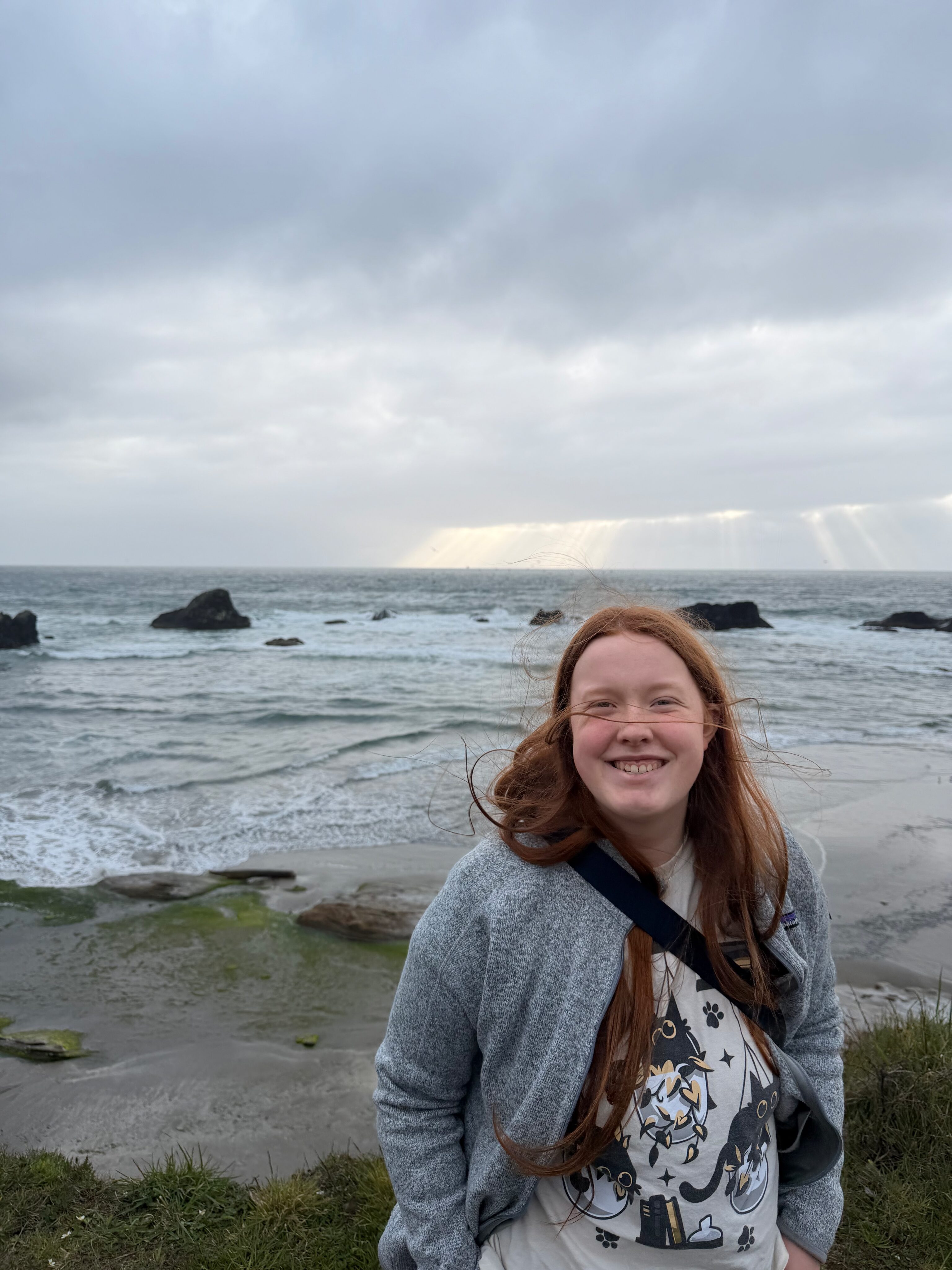 Cami standing at Seal Rock at sunset with the Oregon Coast behind her.