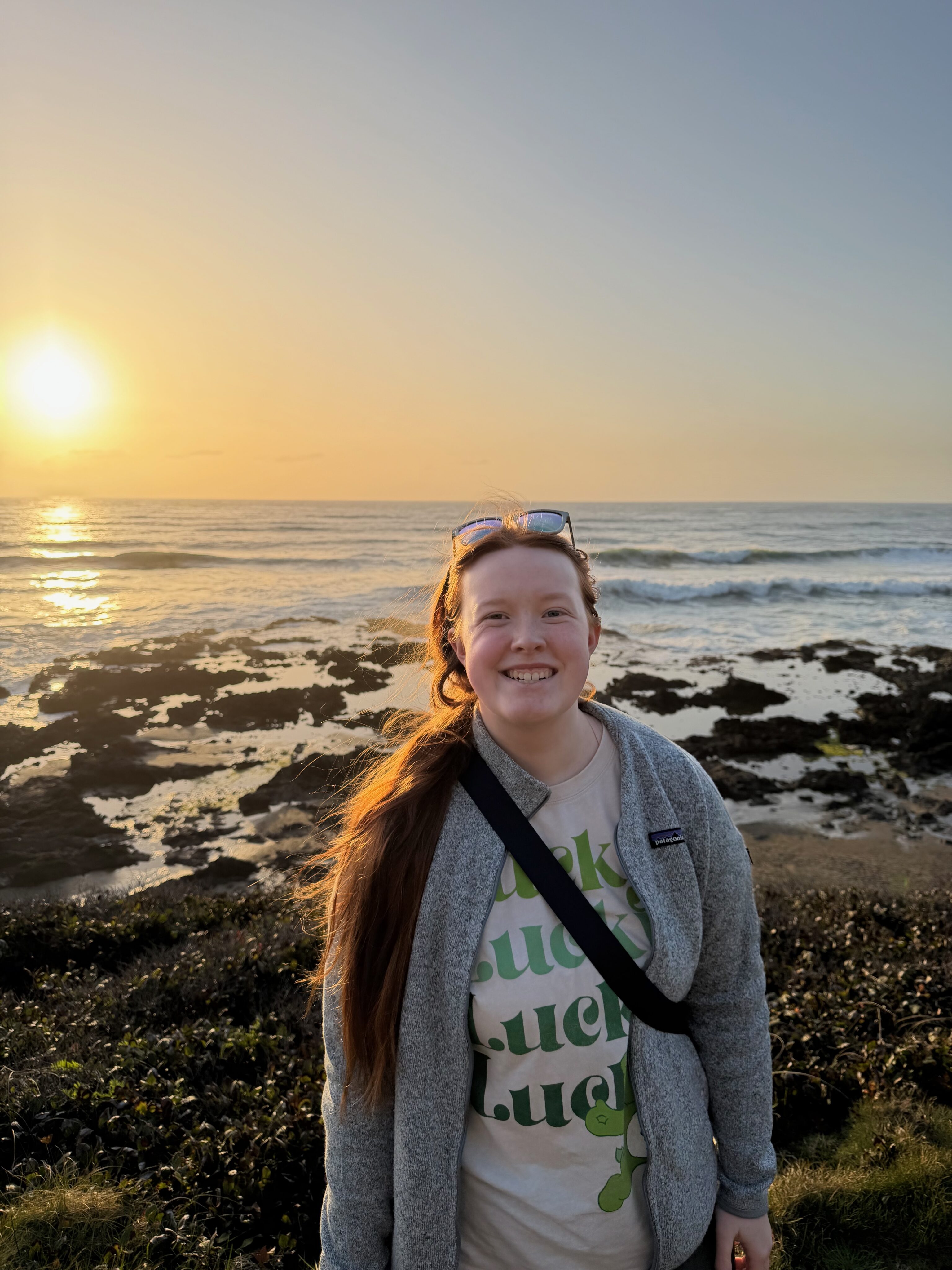 Cami standing near Thor’s Well on the Oregon Coast at sunset.