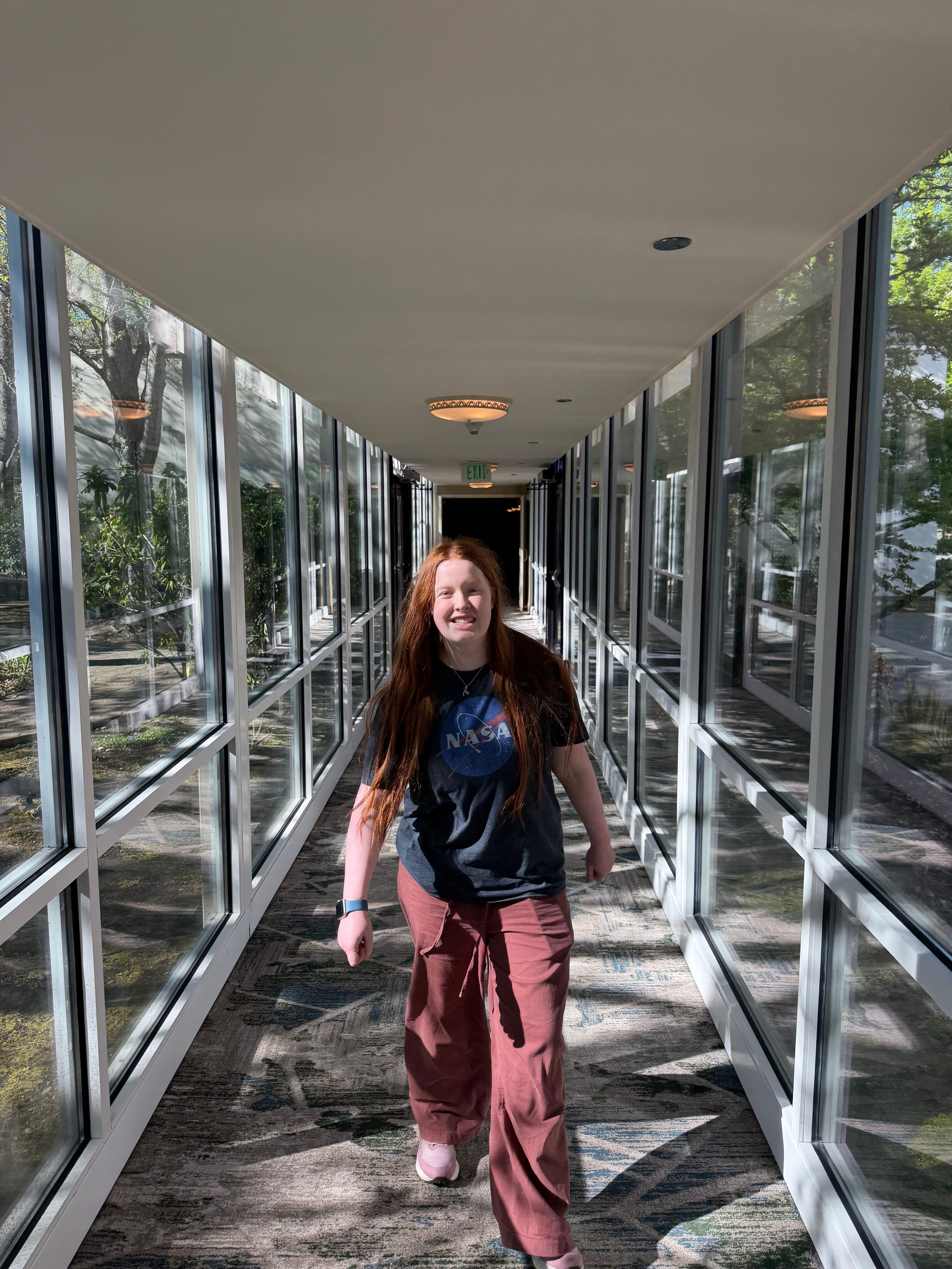Cami walking through a glass hallway at our Seattle airport hotel.
