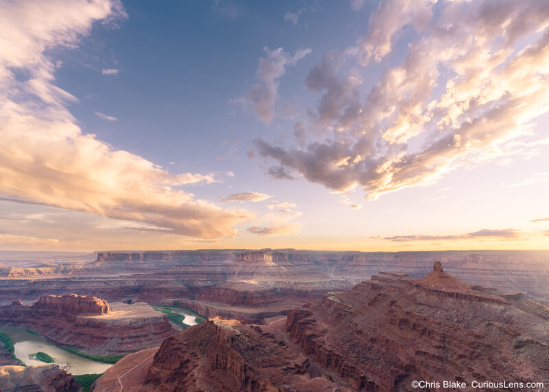 Sunset view from Dead Horse Point State Park with storm clouds, canyon cliffs, and the Colorado River winding through the desert below.